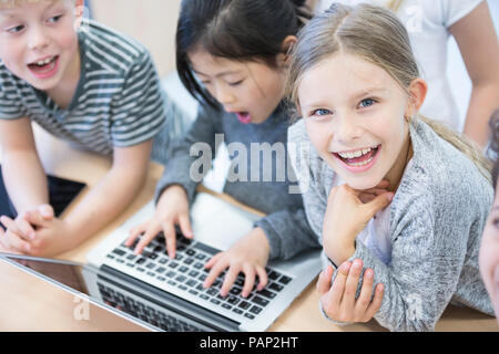 Felice gli studenti usando laptop in classe Foto Stock