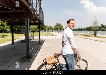 Uomo maturo con moto a riva del Reno Foto Stock