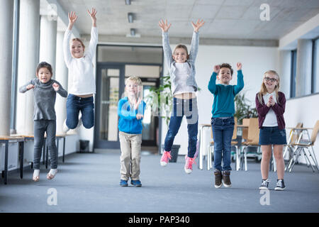 Allievi entusiasti di saltare sul corridoio di scuola Foto Stock
