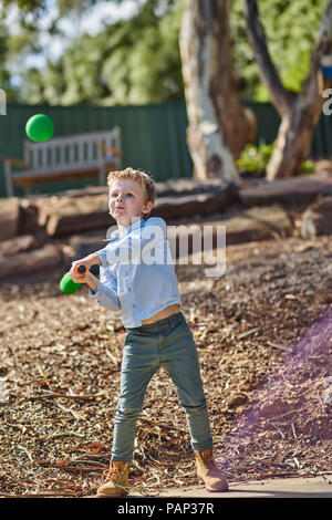 Ragazzo in giardino a giocare con la schiuma di mazza da baseball e la sfera Foto Stock