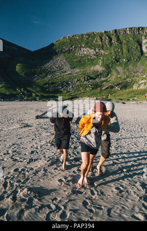 Norvegia Lofoten, Moskenesoy, un gruppo di giovani uomini la preparazione di camp a Kvalvika Beach Foto Stock