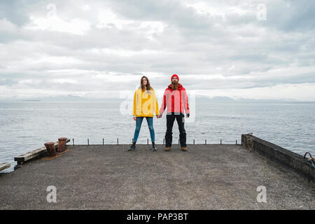 In Islanda, a nord di Islanda, coppia giovane in piedi mano nella mano sul molo Foto Stock