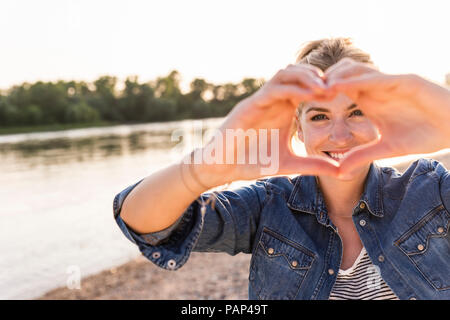 Donna messa a forma di cuore con le mani e le dita Foto Stock