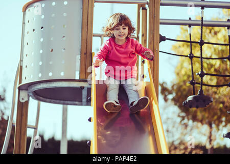 Ritratto di bambina seduti sulla slitta al parco giochi Foto Stock