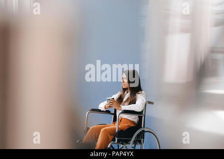 Giovani handicappati donna seduta in carrozzella, guardando preoccupato Foto Stock