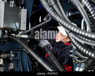 Lavoratore che fissa il tubo flessibile con la chiave per vite Foto Stock