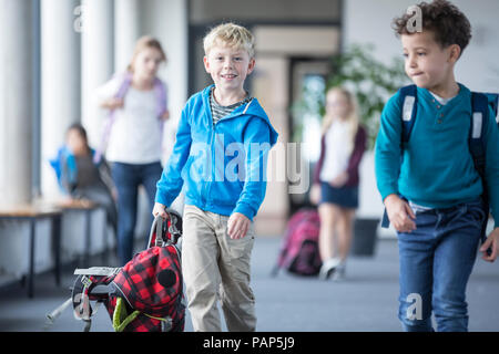 Scolaro con i compagni di classe che lasciano la scuola Foto Stock