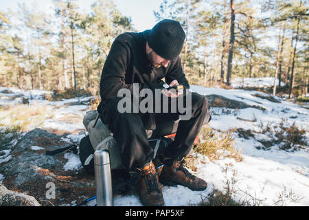 La Svezia Sodermanland, backpacker in appoggio in remoto di paesaggio in inverno utilizzando GPS tracker Foto Stock