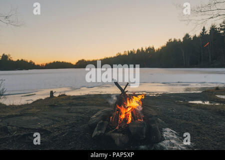 La Svezia Sodermanland, falò a Lakeside in inverno Foto Stock