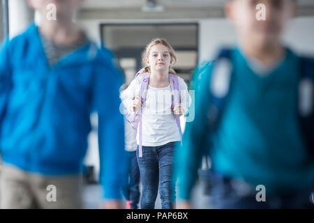 Schoolgirl con i compagni di classe che lasciano la scuola Foto Stock