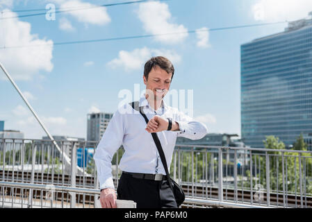 Imprenditore su un ponte controllando il tempo Foto Stock