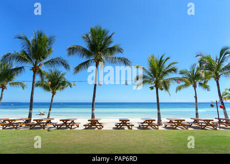 Una perfetta spiaggia di sabbia bianca con tavoli da pic-nic, palme e Resort Outdoor dining - Panglao, Bohol - Filippine Foto Stock