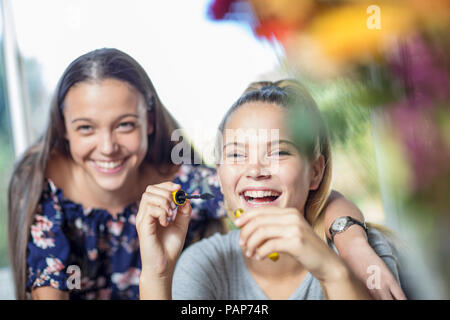 Felice ragazza adolescente guardando amico applicazione di mascara Foto Stock