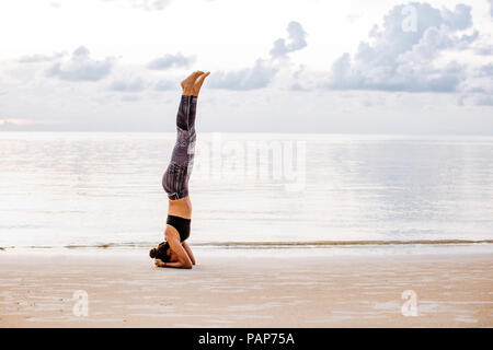Thailandia Koh Phangan, Sportive donna fare yoga sulla spiaggia Foto Stock