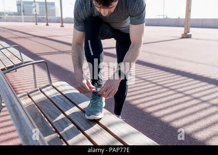 Uomo sportivo lacing le sue scarpe su un banco di lavoro Foto Stock