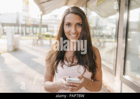 Piuttosto giovane donna utilizza lo smartphone nella città Foto Stock