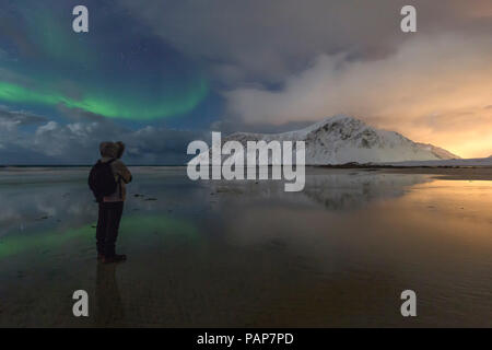 Norvegia Lofoten, Vareid, Flakstad, l'uomo a guardare il tramonto e luci del nord Foto Stock