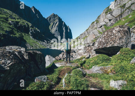 Norvegia Lofoten, Moskenesoy, giovane uomo in piedi di fronte a Litljordtinden Foto Stock