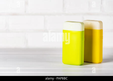 Due di plastica chiuso uno shampoo e balsamo di contenitori, verde e giallo su sfondo bianco. Copia dello spazio. Foto Stock