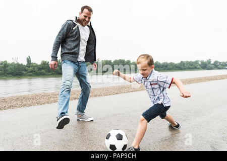 Felice il padre e il figlio a giocare a calcio al Riverside Foto Stock