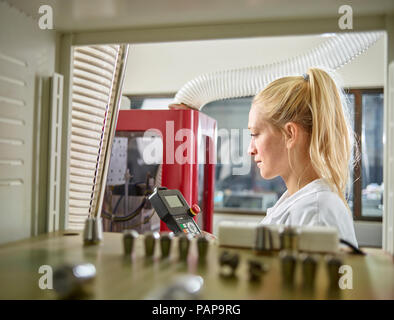 Tecnico femminile mantenendo macchina CNC Foto Stock