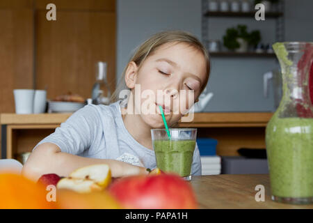 Ragazza seduta in cucina, casalinga potabile frullato di frutta Foto Stock