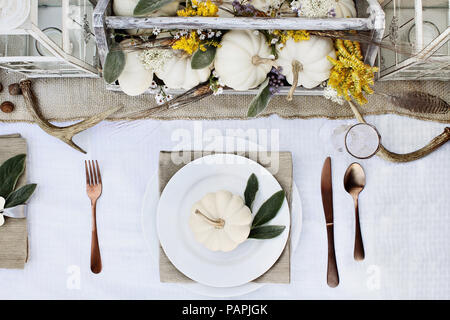 Riservati del Ringraziamento o di luogo di Halloween impostazione a una casa colonica tabella set con mini white zucche, Agnello le orecchie di foglie, palchi e fiori di campo per un Foto Stock