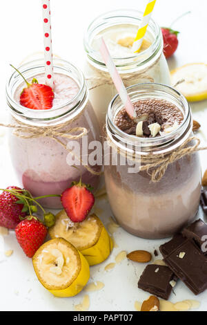 Set di frullato in vasi. Banana cioccolato e fragola frappè con e noci di cocco. Estate dessert. Cibo sano. Foto Stock