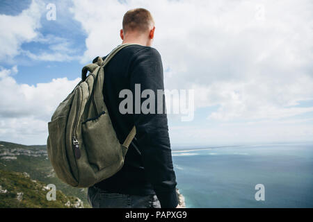 Un turista o viaggiatore con lo zaino è in piedi sulla cima di una collina e ammirare la splendida vista sull'oceano o sul mare. Passeggiate o escursioni. Foto Stock