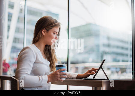 Giovane imprenditrice in un cafe utilizzando tablet Foto Stock