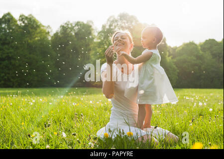 Madre e figlia con blowball sul prato in estate Foto Stock