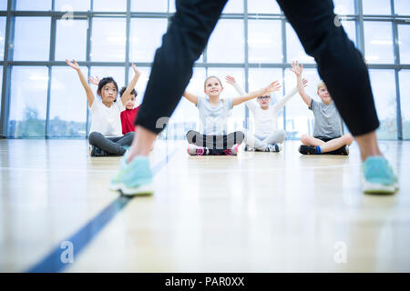 Gli alunni di esercitare nella palestra di classe Foto Stock