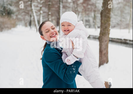 Ritratto di happy Baby girl divertendosi con sua madre nel paesaggio innevato Foto Stock