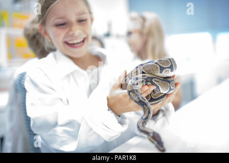 Felice schoolgirl nella classe di scienze azienda snake Foto Stock