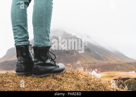 L'Islanda, le gambe della donna in piedi sulla collina Foto Stock