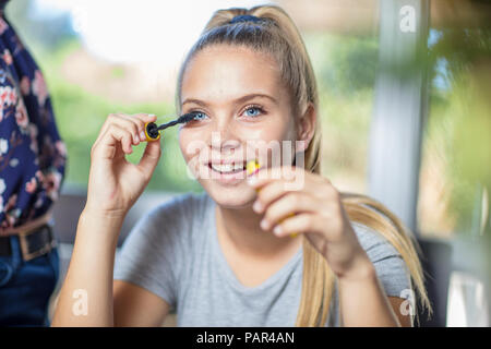 Ritratto di sorridente ragazza adolescente applicazione di mascara Foto Stock