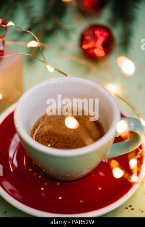 Deliziosa mattina inverno festosa di caffè espresso sullo sfondo verde con decorazioni natalizie e le lucciole , Vista ravvicinata Foto Stock