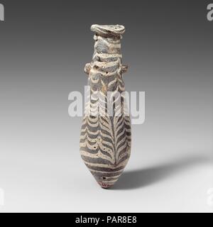 Alabastron di vetro (bottiglia di profumo). Cultura: greco, Mediterraneo orientale. Dimensioni: complessivo: 5 7/16 x 1 1/2a. (13,8 x 3.9cm). Data: 2nd-1st secolo A.C. Traslucide blu chiaro con riflessi verdognoli; bianco opaco sentieri; maniglie di colore indeterminato (blu?). Irregolare, spiralato cerchione-disco con arrotondato il labbro esterno; corpo fusiforme, con irregolare, deformato i lati, espandendo verso il basso, rastremandosi poi in fondo appuntito; due capocorda irregolare maniglie applicate sulla parte superiore del corpo sul sentiero con utensili orizzontali trattini di cui sopra e sotto. Sentiero applicata in modo non uniforme attorno al cerchio e trainati sotto off; un altro percorso collegato Foto Stock