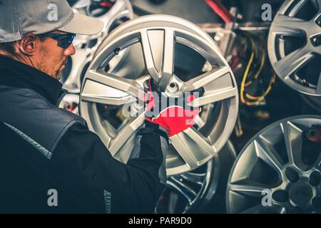 Acquisto di nuovi cerchi in lega e pneumatici stagionali Concetto di Modifica foto. Caucasian Car Service lavoratore con grande cerchio in mani. Foto Stock