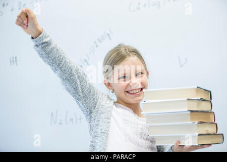 Ritratto di felice schoolgirl trasporto di libri in classe Foto Stock