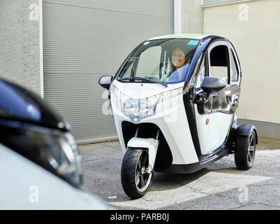 Donna sorridente seduto in bolla elettrico auto Foto Stock