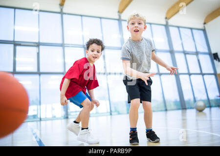 Due scolari giocare a basket in palestra classe Foto Stock