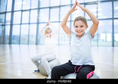 Ritratto di sorridere studentesse seduti sulla palla in palestra classe Foto Stock