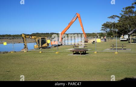 Escavatore idraulico o gru di scavo in acqua in Australia, Coffs Harbour. Lavoratori con macchinari pesanti in azione al sito di lavoro. Foto Stock