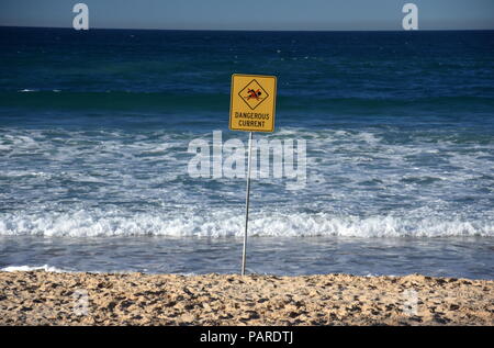 Sydney, Australia - Lug 5, 2018. Un segno legge corrente pericolosa. Nessuna bandiera piscina sulla spiaggia dopo la tempesta. Foto Stock