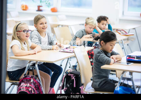 Gli alunni seduti alla scrivania in classe Foto Stock