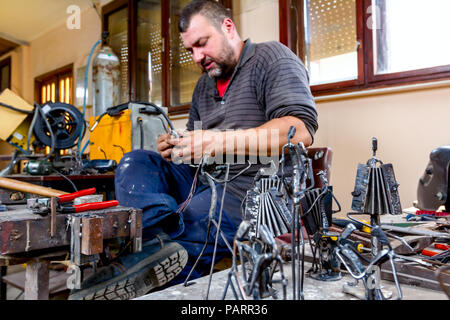 Scultore è rendere le figure creative di musicisti di filo metallico nella sua bottega. Fisarmonicisti suonano insieme. Foto Stock