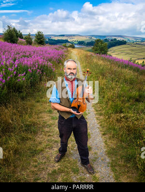 Violino artigiano Steve Burnett pone al mori sopra Haworth con la sua handcrafted Emily Bronte violino in vista del bicentenario del writer che cade il 30 luglio. Il violino artigianale è realizzato dal legno di un vecchio sicomoro che sorgeva nel villaggio di Haworth dove Bronte ha vissuto e scritto. Foto Stock