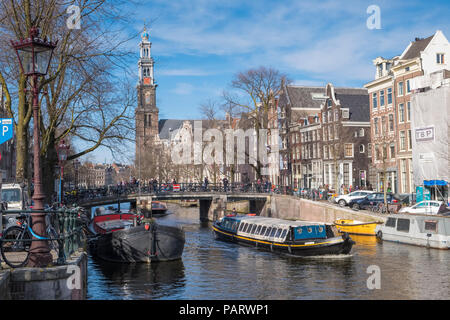 Molte le biciclette su un ponte che si affaccia sul canale di Amsterdam, in Olanda, in Europa con un piacere in barca a vela al di sotto Foto Stock