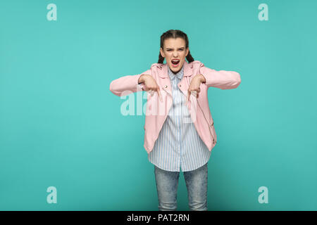 Qui e ora. grave bossy ritratto della bella ragazza carina in piedi con il trucco e la spiralina marrone acconciatura a strisce in maglietta blu camicia rosa. interna Foto Stock